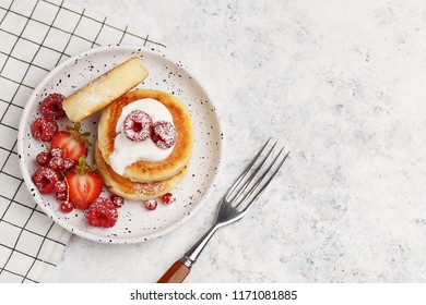 Traditional russian and ukrainian dish for breakfast syrniki. Cottage cheese pancakes with sour cream and fresh berries on white marble background. Top view with copy space