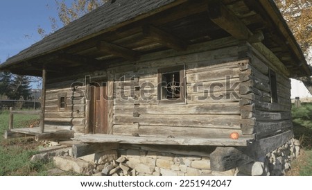 Traditional rustic old wooden house with stone embankment and open porch