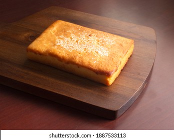 Traditional Salvadoran sweet cheese sponge cake on a dark brown wooden cutting board