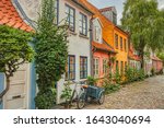 A traditional Scandinavian Cargo bicycle (Christiania Bike) parked at a house entrance in a cozy downtown street by a colorful facade. Danish lifestyle and culture illustration - Aarhus, Denmark