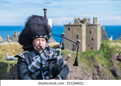 Traditional scottish bagpiper in full dress code at Dunnottar Castle in Stonehaven