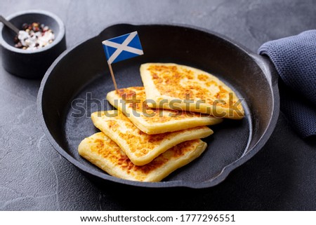 Traditional Scottish tattie potato scones in cast iron pan with Scotland flag. Dark background. Close up.