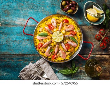 Traditional seafood paella in the fry pan on a wooden old table, top view