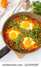 Traditional Shakshuka With Red Vegetables And Green Chopped Cilantro In Skillet. Homemade Food For Dinner With Eggs And Tomatoes.