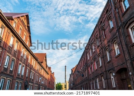 Traditional Silesian tenement house. Red brick architecture. The chimney of the heating plant in the background. Silesian street. Siemianowice Śląskie, Poland
