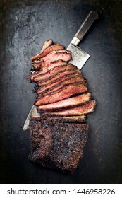 Traditional smoked barbecue wagyu beef brisket offered as top view with knife on an old rustic board with copy space 