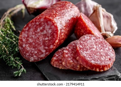 Traditional smoked salami sausage with spices.Salami sausage slices on a black chopping Board. Dark background. - Shutterstock ID 2179414911