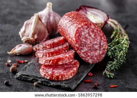 Traditional smoked salami sausage with spices.Salami sausage slices on a black chopping Board. Dark background.