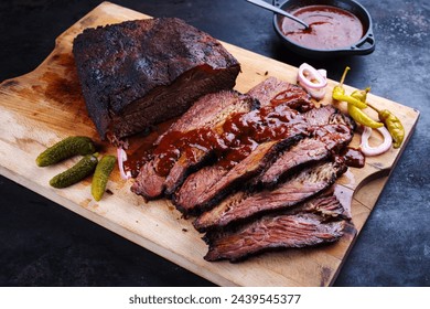 Traditional smoked wagyu beef brisket served with vegetable and spicy barbecue Louisiana sauce served as close-up on a wooden cutting board