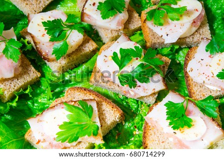 Traditional snack for Russian and Ukrainian people on the holidays. A sandwich with bacon, garlic and parsley under the glass of genuine Russian vodka
