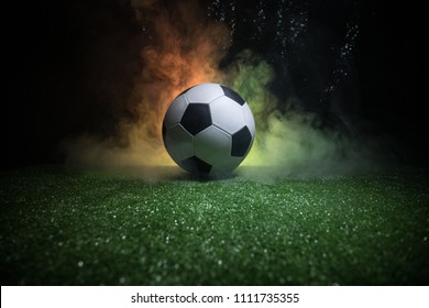 Traditional soccer ball on soccer field. Close up view of soccer ball (football) on green grass with dark toned foggy background. Selective focus