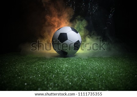 Traditional soccer ball on soccer field. Close up view of soccer ball (football) on green grass with dark toned foggy background. Selective focus