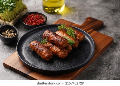 Traditional south european skinless sausages cevapcici made of ground meat and spices on black plate on dark wooden board, with thyme and watercress salad - Shutterstock ID 2157432729