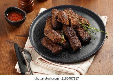 Traditional South European Skinless Sausages Cevapcici Made Of Ground Meat And Spices On Black Plate On Kitchen Towel With Thyme