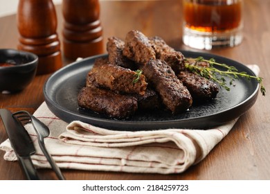 Traditional South European Skinless Sausages Cevapcici Made Of Ground Meat And Spices On Black Plate On Kitchen Towel With Thyme