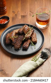 Traditional South European Skinless Sausages Cevapcici Made Of Ground Meat And Spices On Black Plate On Dark Wooden Board, With Thyme