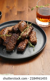 Traditional South European Skinless Sausages Cevapcici Made Of Ground Meat And Spices On Black Plate On Dark Wooden Board, With Thyme