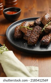 Traditional South European Skinless Sausages Cevapcici Made Of Ground Meat And Spices On Black Plate On Dark Wooden Board, With Thyme