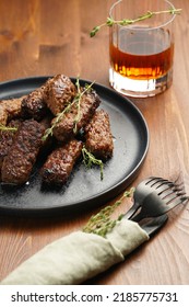 Traditional South European Skinless Sausages Cevapcici Made Of Ground Meat And Spices On Black Plate On Dark Wooden Board, With Thyme