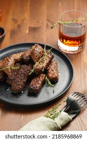 Traditional South European Skinless Sausages Cevapcici Made Of Ground Meat And Spices On Black Plate On Dark Wooden Board, With Thyme