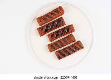 Traditional South European Skinless Sausages Cevapcici Made Of Ground Meat And Spices, Vegan Substitute Made Of Soy Protein, Five Pieces On White Plate On White Background, Top View