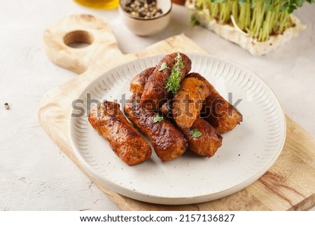 Traditional south european skinless sausages cevapcici made of ground meat and spices on white plate on light wooden board, with thyme and watercress salad