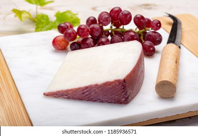 Traditional Spanish cheese, one piece of Murcian wine cheese from goat milk with rind washed in red wine, served with fresh ripe grapes - Powered by Shutterstock