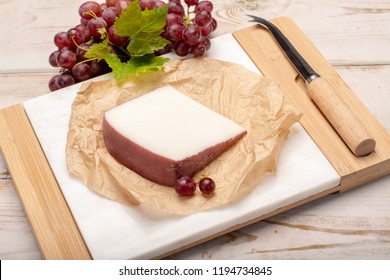 Traditional Spanish cheese, one piece of Murcian wine cheese from goat milk with rind washed in red wine, served with fresh ripe grapes - Powered by Shutterstock