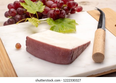 Traditional Spanish cheese, one piece of Murcian wine cheese from goat milk with rind washed in red wine, served with fresh ripe grapes - Powered by Shutterstock