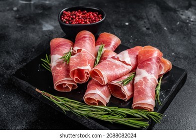 Traditional Spanish Jamon Serrano ham on marble board. Black background. Top view