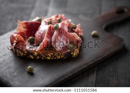 Traditional Spanish Jamon Serrano ham, Prosciutto Crudo, Parma ham, Italian antipasto, served on toasted bread.