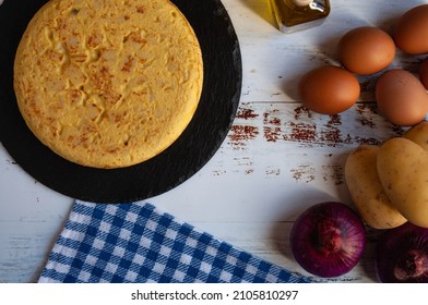 Traditional Spanish Omelette And The Ingredients For Its Preparation On A Wooden Table. Aerial View