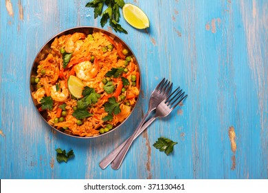 Traditional spanish paella dish with seafood, peas, rice and chicken over grunge blue background. Top view. Selective focus - Powered by Shutterstock