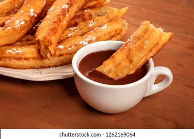 Traditional Spanish Porras Dipped In Hot Chocolate, A Typical Madrid Sunday Breakfast, On A Dark Rustic Wooden Background With Copy Space