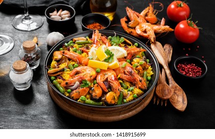 Traditional spanish seafood paella in the fry pan on a black wooden  table.