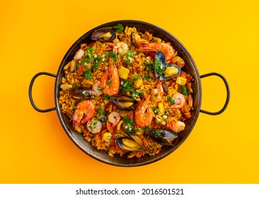 Traditional spanish seafood paella with rice, mussels, shrimps in a pan on white background. view from above, flat lay