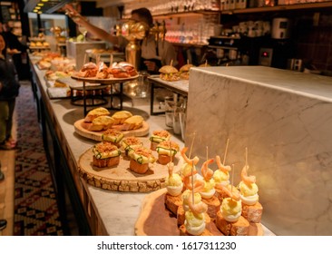 Traditional Spanish snacks or tapas called pintxos in a bar counter in San Sebastian, Basque country, Spain. Basque national cuisine in a typical cafe or restaurant or tapas bar.