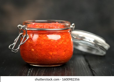 Traditional Spicy Harissa Sauce In A Glass Jar On A Dark Background. Maghreb Cuisine.