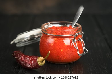 Traditional Spicy Harissa Sauce In A Glass Jar On A Dark Background. Maghreb Cuisine.