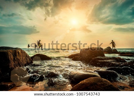 Traditional Sri Lankian sea fishermans at work under sunset sunlight. Most popular cultural icon for travellers on the ocean beaches in Sri Lanka.