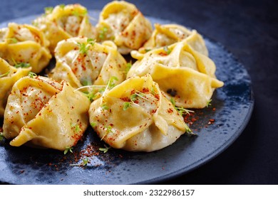 Traditional steamed Kazakh manti garnished with mincemeat and sumah served as close-up on a Nordic design plate 