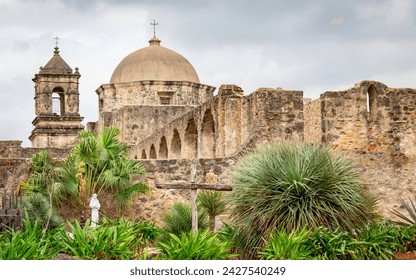 Traditional stone architecture of the old Mission San Jose located at the San Antonio Mission Historical Park in San Antonio Texas. Picture is taken on a cloudy overcast day with lush green plants - Powered by Shutterstock