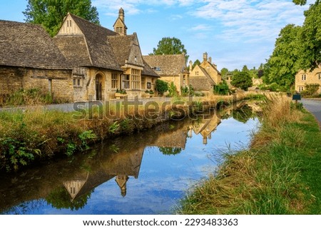 Traditional stone houses reflecting in a river on a summer day in Lower Slaughter village in Cotswolds, England, United Kingdom. Lower Slaughter village is one of the most visited sites in Cotswolds.