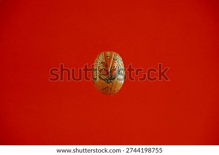 A traditional straw-crafted Easter egg floating on a red background