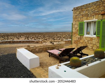 Traditional style hotel in a desert, Cape Verde. Old rebuilt house with stone walls, cozy terrace with two sunbeds and wild view. Selective focus on the details, blurred background. - Shutterstock ID 2052446483