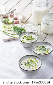 Traditional summer cold soup of homemade yogurt, cucumbers and fresh herbs on a wooden table
