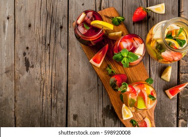 Traditional summer drink sangria - red, pink and white. With champagne, pink and red wine, strawberries, oranges, lemon, green apple and grapefruit. On a wooden rustic table, copy space top view
