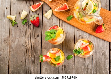 Traditional Summer Drink White Sparkling Sangria. With Champagne, Strawberries, Oranges, Lemon, Green Apple And Grapefruit. On A Wooden Rustic Table, With A Jug And Ingredients. Copy Space Top View