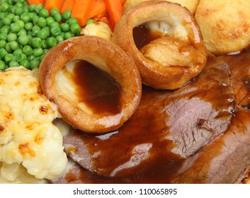 Traditional Sunday Roast Beef Dinner With Yorkshire Puddings And Gravy.