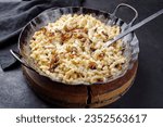 Traditional Swabian cheese spaetzle with fried onions served as close-up in a cast-iron frying pan on a rustic black board 